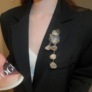 Detail of a gold floral tassel brooch with rhinestones pinned on a black blazer suit
