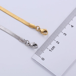 Detail view of gold and silver 4mm flat snake bone chains with ruler measurement