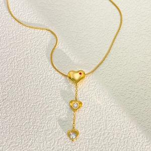 Golden heart pendant necklace with snake chain and zircon stones on a white background