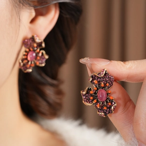 Gros plan détaillé des boucles d'oreilles fleurs vintage avec strass violets et gemmes