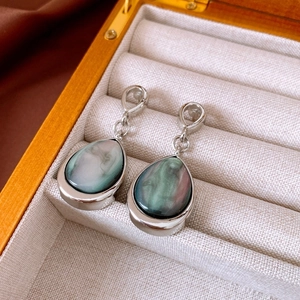 Detailed macro view of silver water drop earrings with iridescent blue shell inlay