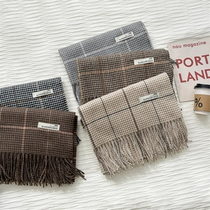 Detail of four houndstooth scarves with fringes and woven SUPERWOMAN labels in various colors