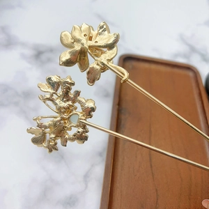 Detailed view of golden flower and butterfly hair pin with ornate vintage engravings