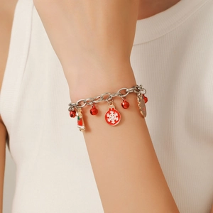 Close-up of Christmas charm bracelet with red and white enamel bells, reindeer and snowflakes