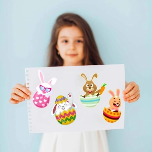Niña sostiene pegatinas de huevos de Pascua con conejos lindos y diseños coloridos