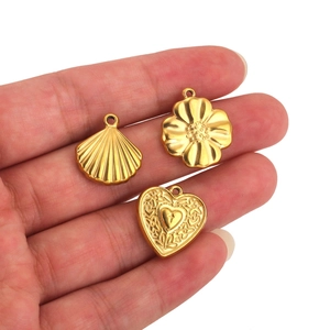 Golden stainless steel shell, flower and heart pendants with relief texture in hand