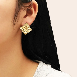 Vue détaillée de boucles d'oreilles carrées dorées à vagues portées pour un look chic