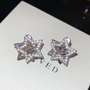 Detailed macro view of the sparkling silver star earrings with saturn orb design