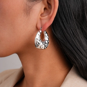 Hammered chunky silver hoop earrings with irregular geometric texture in metallic finish