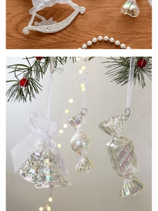 Macro detail of iridescent acrylic Christmas ornaments with bows hanging on pine branches