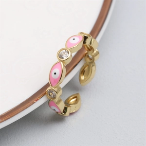 Close-up of golden adjustable evil eye ring with pink enamel and sparkling zircon detail