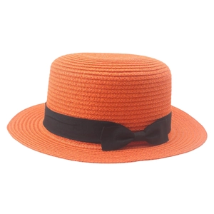Detail of orange straw boater hat featuring a black grosgrain ribbon and side bow