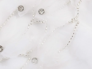 Détail de tulle blanc avec perles argentées et broderie de strass étincelants
