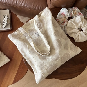 Detail of cream canvas tote bag with 3D polka dot texture and inner woven brand label