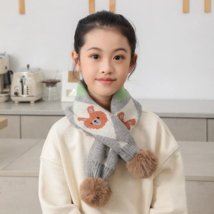Détail d'une écharpe en maille douce pour enfants avec motif d'ours et pompons soyeux