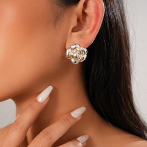 Detail of flower shaped gold and silver stud earrings shown on model for elegant look