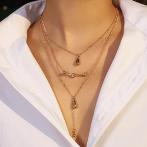 Three-layer gold layered necklace with teardrop pendants and rhinestone bar on a model