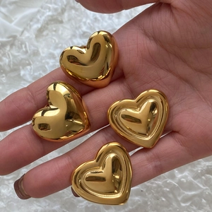 Detailed view of four glossy golden heart-shaped metal charms for earring making