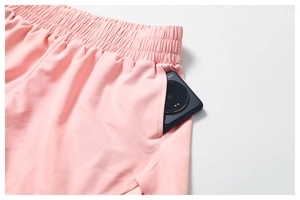 Gros plan d'un short de sport rose avec taille élastique et poche contenant un smartphone