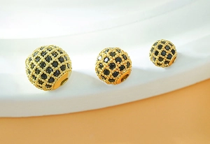 Detailed view of three golden micro-pave spherical beads with black cubic zirconia