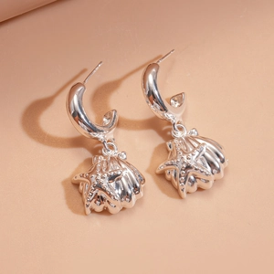 Detail of silver starfish and seashell drop earrings with high-quality metal textures