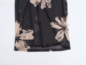 Détail de la robe élégante en résille noire avec de grands imprimés floraux beiges et l'ourlet