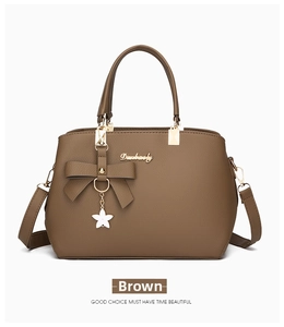 Detail of caramel leather handbag with lychee texture and bow star pendant