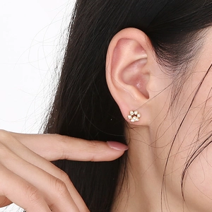 Close-up of a gold cat paw stud earring with crystals worn by a model