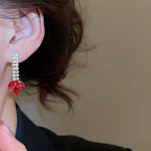 Close-up of elegant gold tassel earrings with zircon and red marquise-cut gems on model