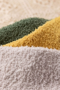 Close-up of thick coral fleece fabric in green, yellow and beige showing soft texture