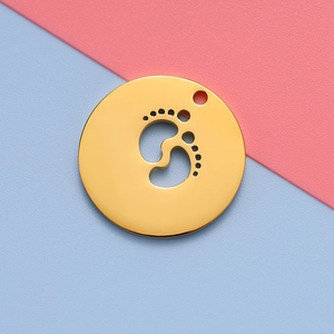 Polished gold round pendant with hollow baby footprint on pink and blue background