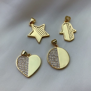 Gold plated Hamsa hand heart star zircon charms set on soft white fabric background