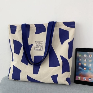 Detail of canvas tote bag with rabbit print and blue block color next to tablet
