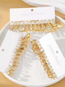 Detailed set of gold finish hoop earrings and pearl studs on a white ceramic display