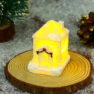 Detail of white glowing resin Christmas snow house with red bow and warm LED lights