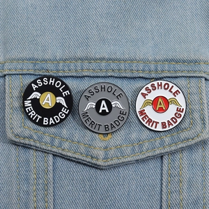 Détail de trois badges métalliques épinglés sur la poche d'une veste en jean
