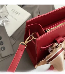 Detail of red leather handbag with gold hardware and decorative striped silk scarf