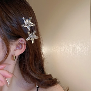 Detailed view of silver star hair clips with hammered texture and embossed lettering
