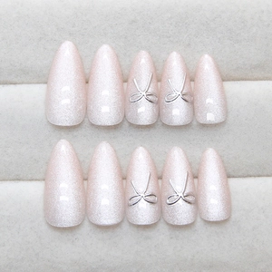 Pink cat eye almond press-on nails with silver 3D bow charms and shimmering finish