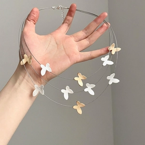 Close-up of triple-layered butterfly pendant necklace in matte gold and silver finish