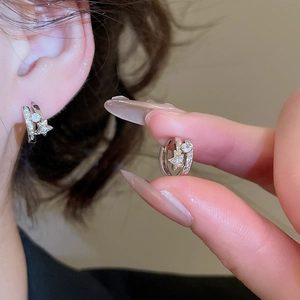 Gros plan de boucles d'oreilles créoles argentées avec étoiles et strass brillants