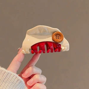 Pince à cheveux mignonne beige bouton fromage avec dents rouges tenue dans la main