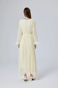 Vue arrière d'une robe longue plissée crème avec manches à plumes et détails perlés