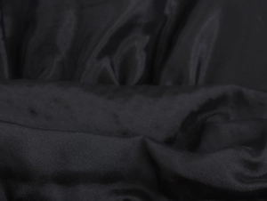 Dettaglio ravvicinato del tessuto organza nero liscio con trama setosa e pieghe