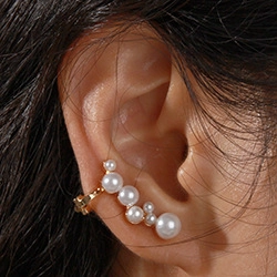 Detailed view of a gold-plated ear cuff featuring elegant pearls on a female model's ear