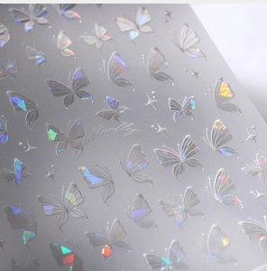 Dettaglio di adesivi per unghie a farfalla laser aurora con texture 3D e riflessi olografici