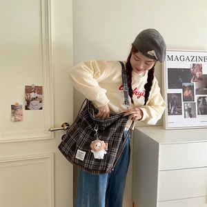 Detailed view of brown plaid crossbody bag with a cute plush charm accessory