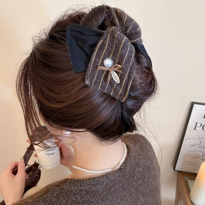 Détail de la pince à cheveux avec nœud en tissu marron foncé et perle sur le modèle