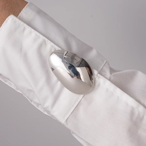 Macro detail of minimalist silver oval cufflinks showing mirror-polished finish on white shirt