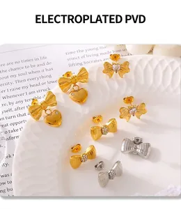 Close-up of gold and silver bow stud earrings with PVD plating and micro-inlaid stones